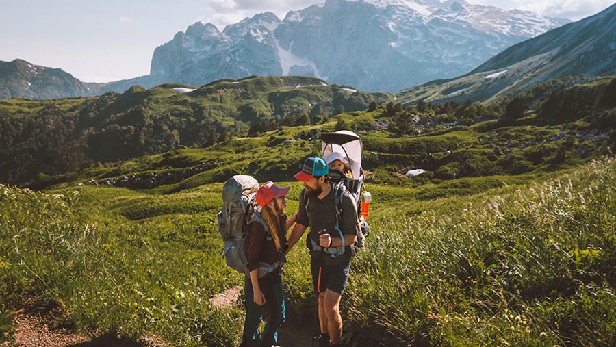 Familie beim Wandern, die überlegt: Urlaub mit Baby, wohin?